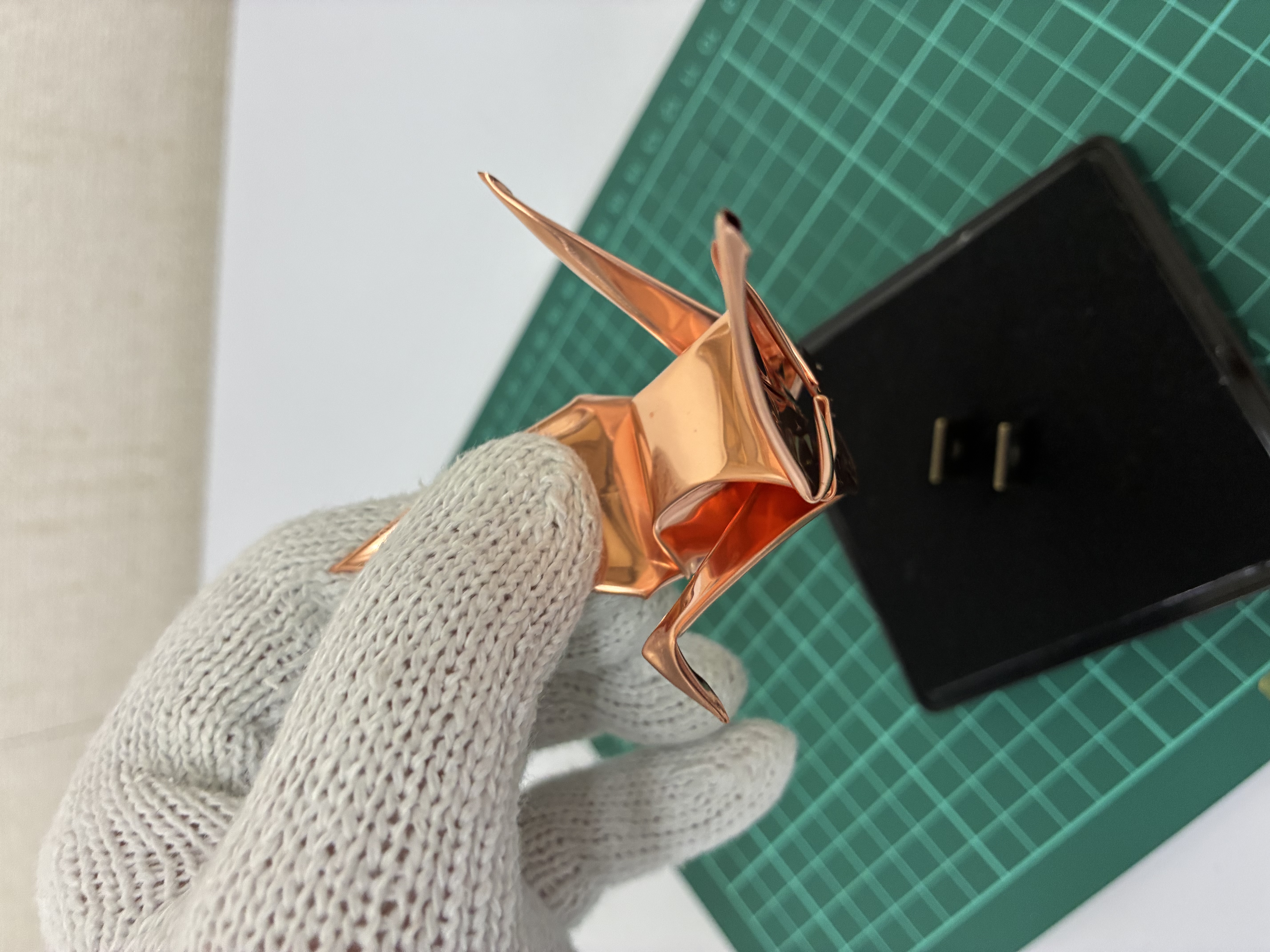 手袋を着けて折り鶴の作品を仕上げる手元