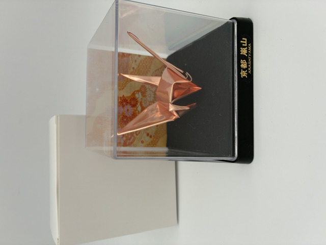 白い背景に箱と並ぶ京都嵐山の折り鶴の工芸品